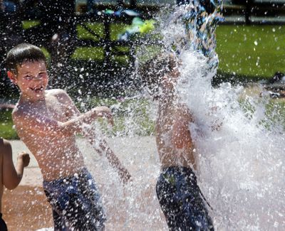 Donald Pulliam, 7, left, makes sure his brother Kallen, 5, gets the full splash from a bucket of cold water as temperatures climbed Thursday at the Merkel Sports Complex splash pad in Spokane. The National Weather Service is forecasting highs of 97 today, 100 Saturday and 103 Sunday. (Dan Pelle)