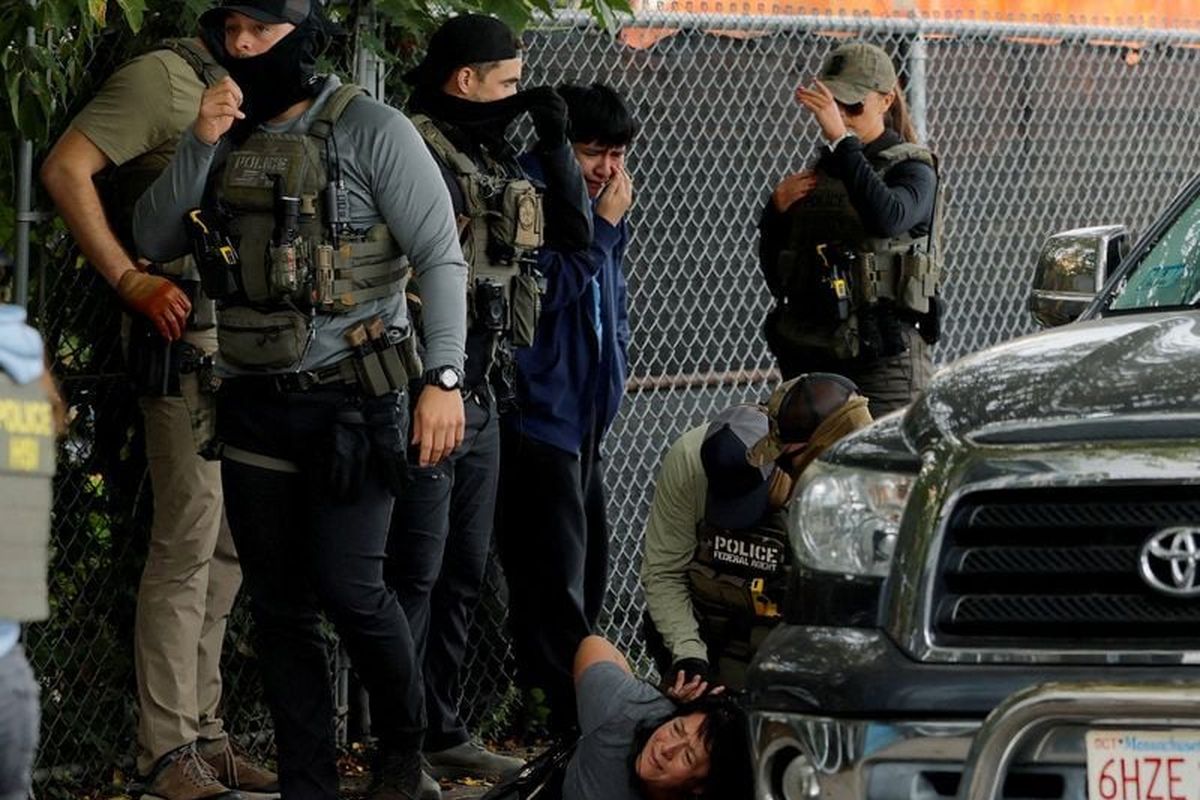 Federal agents, including U.S. Marshals, FBI agents and HSI agents, detain a woman as her son cries beside her, during an immigration enforcement raid Friday in Chelsea, Mass. The agents later released the woman at the scene because she is reportedly a legal U.S. resident and she was taken to the hospital for evaluation. (Brian Snyder)