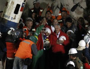 Miner Luis Urzua, the last miner to be rescued, center wearing green, celebrates next to Chile's President Sebastian Pinera after being rescued from the collapsed San Jose gold and copper mine where he had been trapped with 32 other miners for over two months near Copiapo, Chile, Wednesday Oct. 13, 2010. The 69-day underground ordeal reached its end Wednesday night after 33 trapped miners were hauled up in a cage through a narrow hole drilled through 2,000 feet of rock. (Roberto Candia / Associated Press)