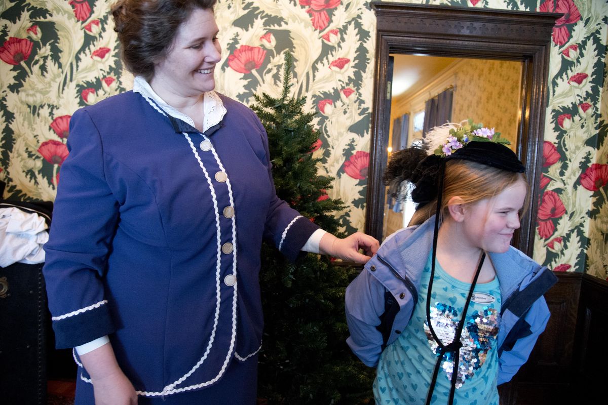 Bailey Crandall, 8, right, grimaces after actress Janean Jorgensen, playing Mrs. Grace Campbell, puts stylish velvet hat on her head at the historic Campbell House Saturday, Dec. 19, 2015. The mansion, operated as a living history exhibit by the Northwest Museum of Arts and Culture, was full of visitors Saturday who got to experience the life of a wealthy Spokane family a century ago with the help of actors like Jorgensen who portrayed historical characters associated with the house. (Jesse Tinsley / The Spokesman-Review)
