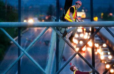 
Workers hang a sign Thursday to alert motorists of traffic revisions for  Interstate 90 roadwork, set to begin Monday. 
 (Kathryn Stevens / The Spokesman-Review)