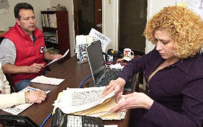 
Maria Carrillo, right, a financial consultant at El Centro in Kansas City, Kan., shuffles through a pile of paperwork as she consults with Guillermo Martinez about his progress on buying a house. 
 (Associated Press / The Spokesman-Review)