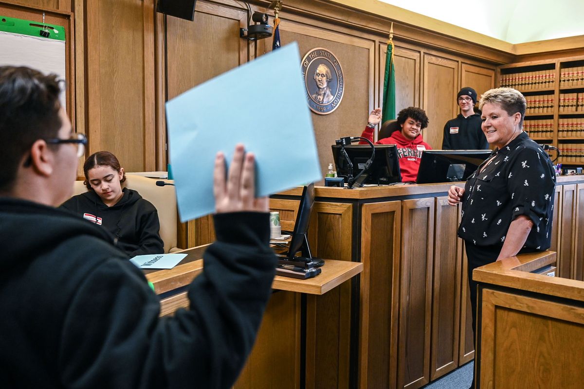 Spokane County Superior Court Judge Annette S. Plese, right, oversees a swearing-in demonstration with Ashden Burrola, of Salk Middle School, right, and Layla Hubbard, of Yasuhara Middle School, on the witness stand. Drevin Burford-Dodd, of Chase Middle School in red, and Alanzo Ramirez, of Salk Middle School wearing the hat on the judge