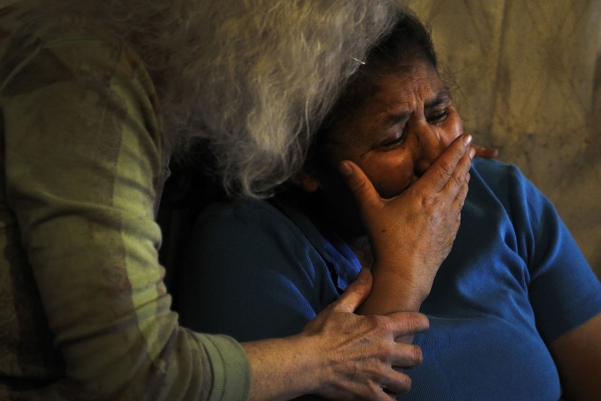 Charlotte Corral breaks down in tears while speaking about her husband, Chico, in their home on the Spokane Reservation. Sandra Belvail, a volunteer advocate who is helping Chico make a radiation compensation claim, offers comfort. (Jed Conklin)