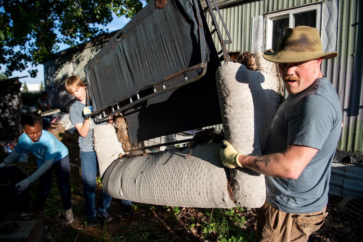 Chris Bovey, right, and Nathan Headrick, 16, carry an old couch to a trailer for disposal as members of the God Squad, a group of community volunteers, clean up a yard, Thursday, May 23, 2019, in Airway Heights. The crew is dedicated to helping people who can’t do chores or jobs for themselves and were clearing a yard where years of garbage had accumulated and the owner unable to get the place cleared. (Jesse Tinsley / The Spokesman-Review)
