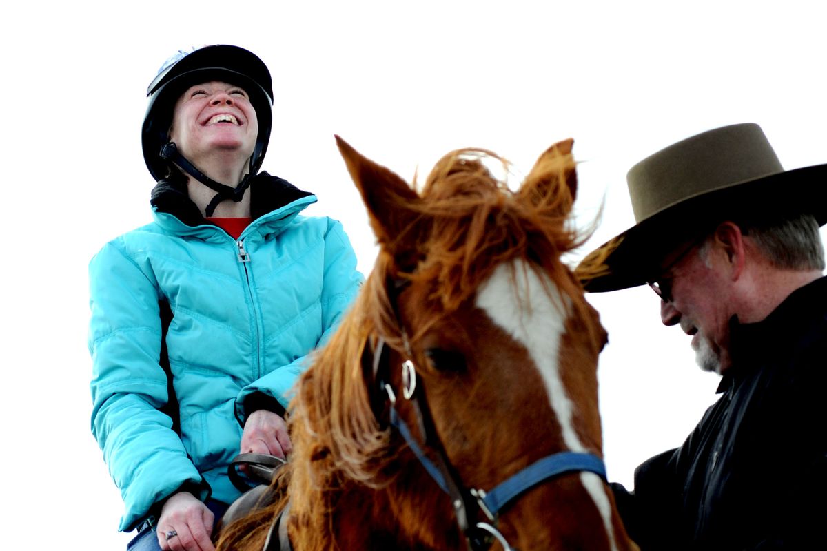 Kathi White, of Post Falls, prepares for a ride with the help of volunteer Bukre Horner at Equine TLC in Post Falls last week. Equine TLC offers therapy to people with disabilities. (PHOTOS BY KATHY PLONKA)