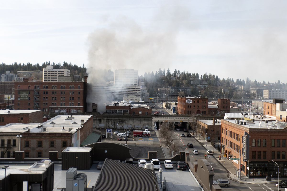 Flames and smoke still arise from the rubble several hours after an early morning fire in a building on the 900 block of W. Railroad Alley Avenue between Monroe and Lincoln streets Thursday in downtown Spokane.  (Jesse Tinsley/The Spokesman-Review)