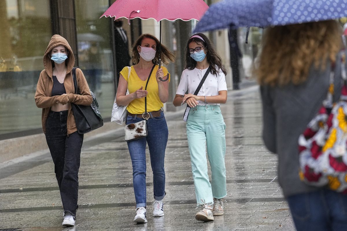 People wearing a face masks to protect against coronavirus walk along the Champs Elysees avenue in Paris, Monday, July 12, 2021. France