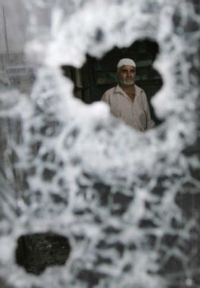 
An Iraqi is seen through a bullet-riddled window in Sadr City  on Saturday, after overnight clashes killed at least 12 and injured 71. Associated Press
 (Associated Press / The Spokesman-Review)