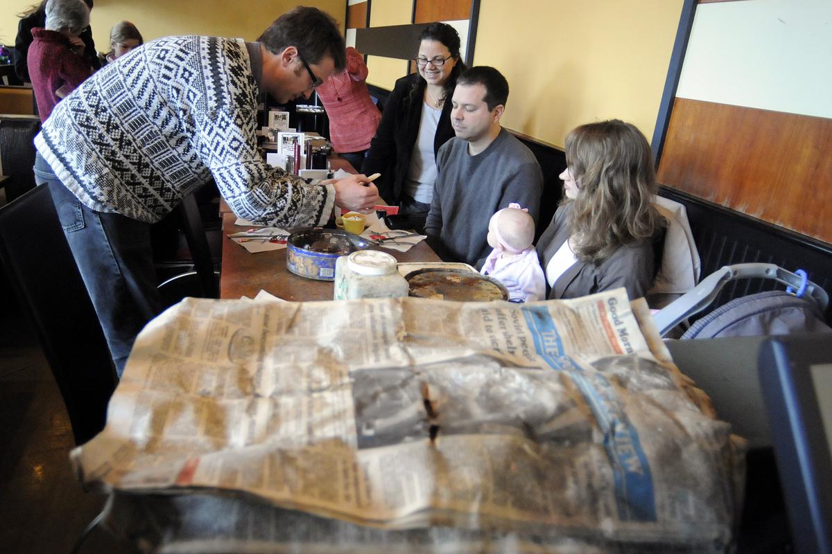 Garrett Smith, left, opens one of three time capsules buried in Riverside State Park that he and some former sixth-grade classmates unearthed and opened Monday. The group buried the items in 1986.  (Christopher Anderson)