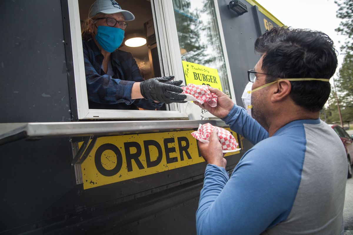 D-Bess Food Truck co-owner Cindy Bessey serves truck driver Tony Valdez two free burgers on Sunday, April 5, 2020 at the westbound rest stop between Post Falls and Coeur d
