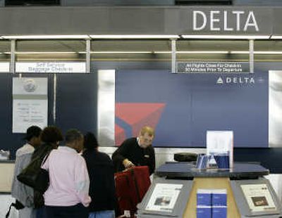 
A Delta worker helps travelers Tuesday at the Seattle-Tacoma International Airport. Associated Press
 (Associated Press / The Spokesman-Review)