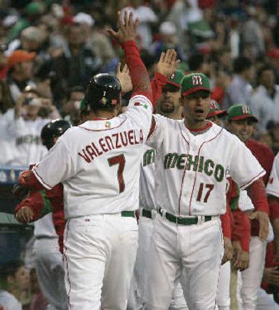 
Mexico's Mario Valenzuela is greeted by teammate Juan Castro after scoring on a fly-out hit by Jorge Cantu in the third inning.
 (Associated Press / The Spokesman-Review)