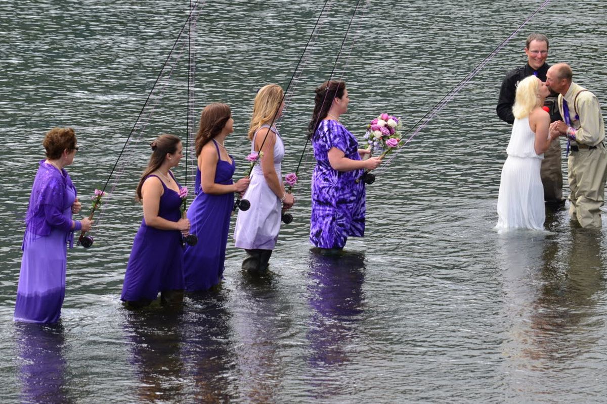 Bridesmaids look on as Kadie and Dake Schmidt, right, exchange a kiss at the end of their wedding ceremony Saturday, Aug. 3, 2013, in Kodiak, Alaska