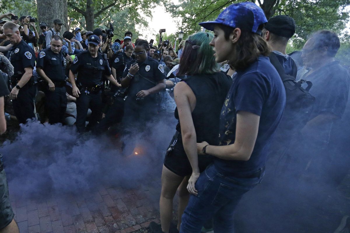 Police and protesters react to a smoke bomb during a rally to remove the confederate statue known as Silent Sam from campus at the University of North Carolina in Chapel Hill, N.C., on Monday, Aug. 20, 2018. (Gerry Broome / AP)