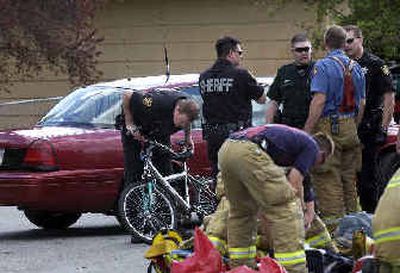 
Deputy Greg Lance takes a close look at a bicycle at the corner of Best and Wellesley in Spokane Valley on Wednesday. A 17-year-old girl riding the bicycle reportedly collided with a vehicle. The injured girl was taken to the hospital in critical condition, authorities said. 
 (Liz Kishimoto / The Spokesman-Review)