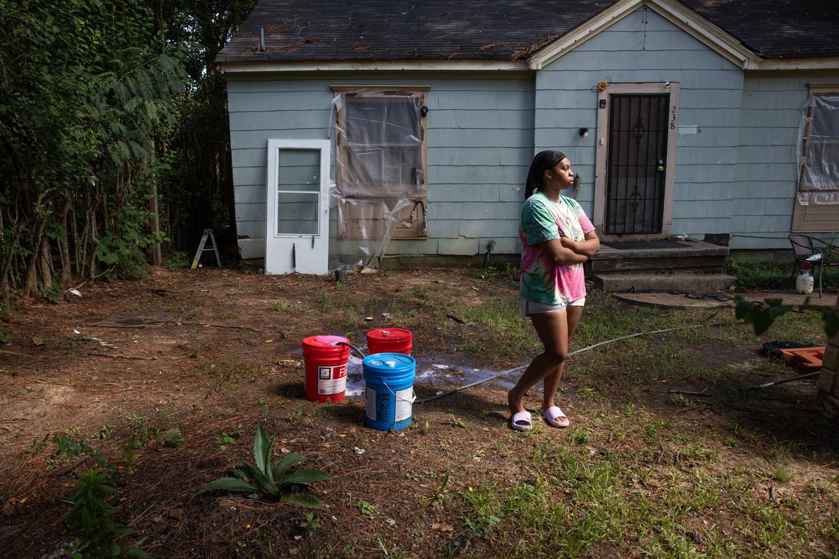 Seresa McCaskill cleans and refills buckets of water in her front yard in Jackson, Miss., on Wednesday. After a water treatment plant pump failure, McCaskill is stocking buckets of water to flush toilets in case water pressure drops. (Camille Lenain/For The Washington Post)