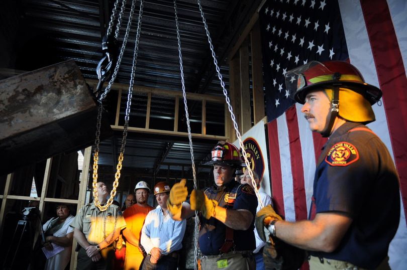 Spokane Valley Fire Department Capts. Pat Schaffer, right, and Tag Baugh hoist a 1,200-pound steel beam that was recovered from the World Trade Center into place at the department's new administration building Sunday.  (J. Bart Rayniak)