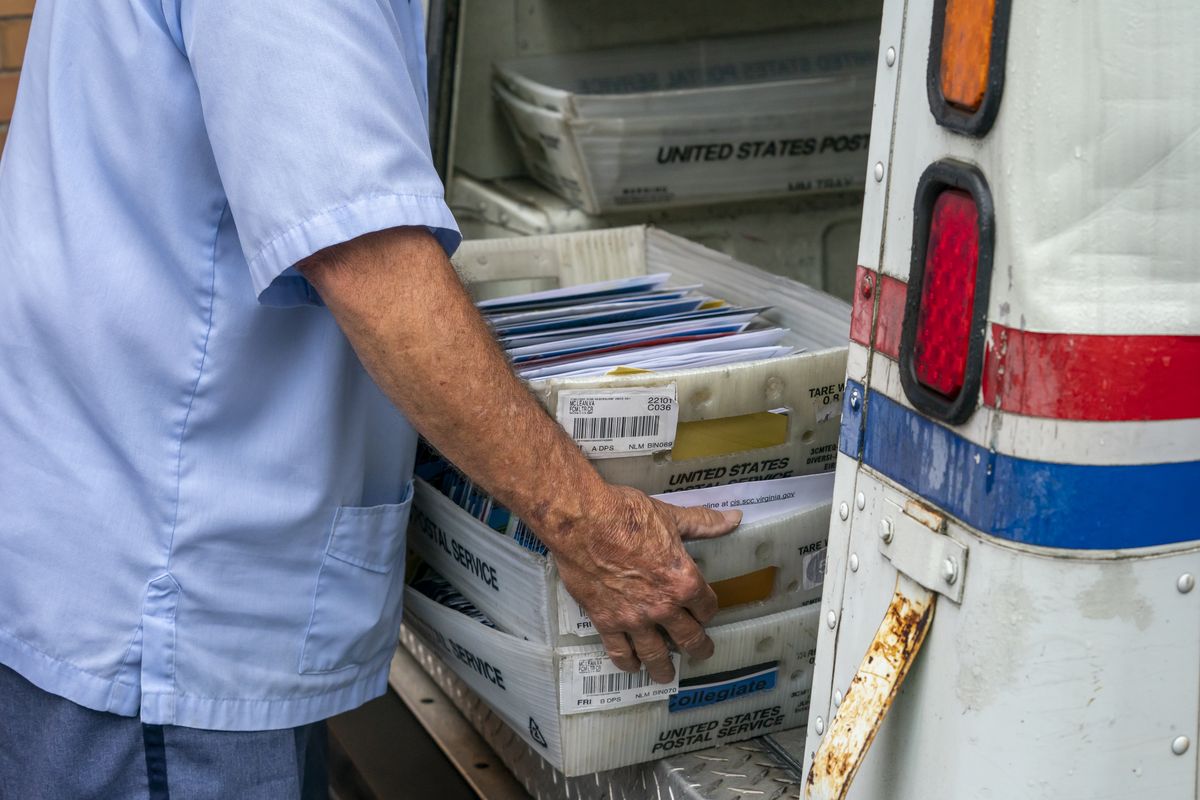 FILE - In this July 31, 2020, file photo, letter carriers load mail trucks for deliveries at a U.S. Postal Service facility in McLean, Va. The success of the 2020 presidential election could come down to a most unlikely government agency: the U.S. Postal Service.  (J. Scott Applewhite)