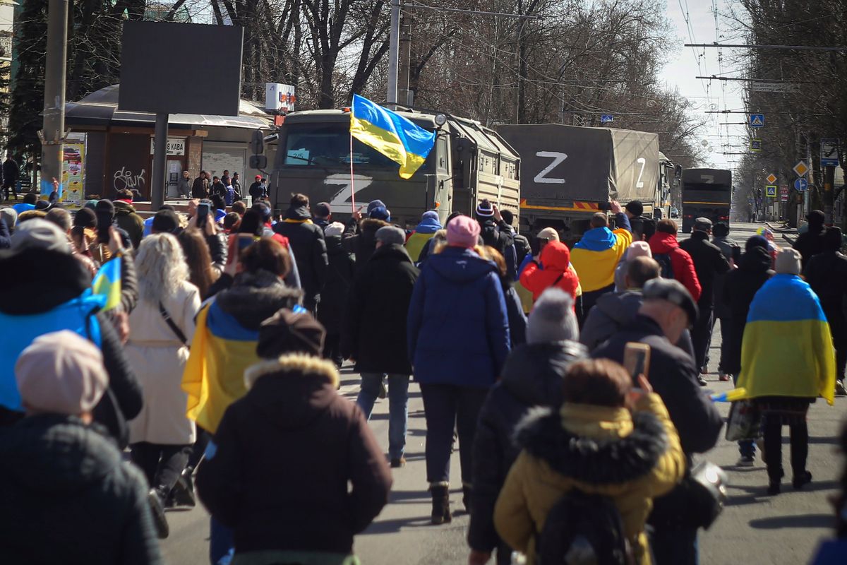 People with Ukrainian flags walk towards Russian army trucks during a rally against the Russian occupation in Kherson, Ukraine, Sunday, March 20, 2022. Ever since Russian forces took the southern Ukrainian city of Kherson in early March, residents sensed the occupiers had a special plan for their town. Now, amid a crescendo of warnings from Ukraine that Russia plans to stage a sham referendum to transform the territory into a pro-Moscow "people