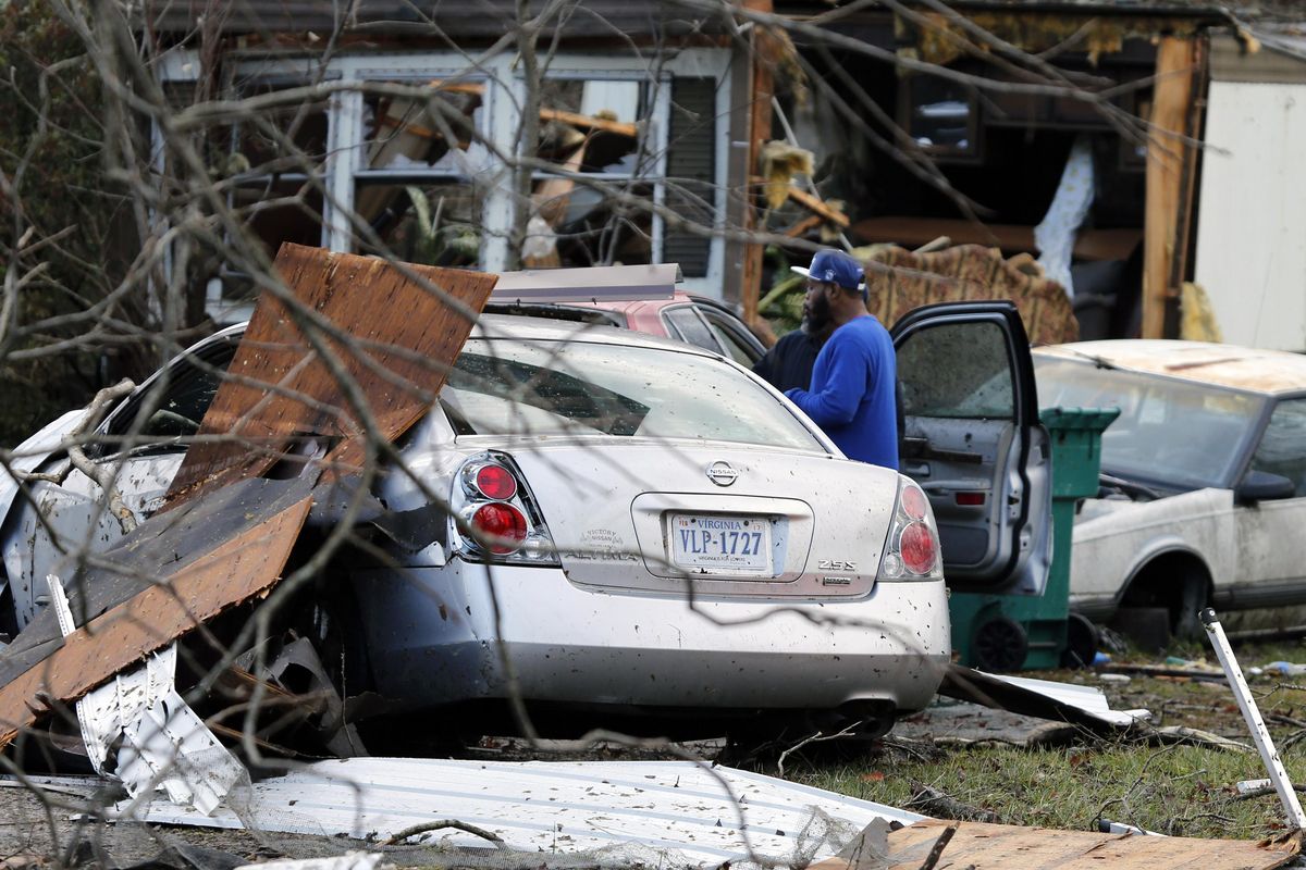 Timothy Williams looks over a car in front of his destroyed mobile home as he walks through debris left by a deadly storm that swept through Waverly, Va., Wednesday. Williams was in the car that he is standing next to when a storm swept through the area. (Steve Helber / Associated Press)
