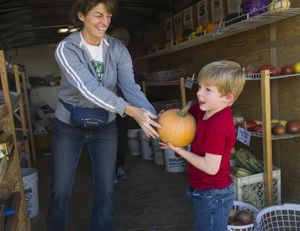 Farmer Robin Jons hands customer Dawson Smith, 5, a pumpkin he just bought Wednesday, at AC Starr Farms. The Otis Orchards farm will present its annual Pumpkins for Pets Fall Festival, a fundraiser for Partners for Pets in Spokane Valley and River City Pet Rescue in Post Falls. There will be hay rides, a corn maze, a trebuchet demonstration, food and music next Saturday. (Colin Mulvany)