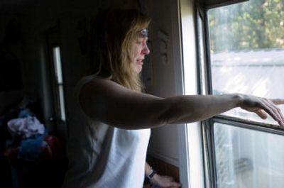 
Stacy Beck looks out her neighbor's window at the wreckage of her home after a fire destroyed it. 
 (Photos by Colin Mulvany/ / The Spokesman-Review)
