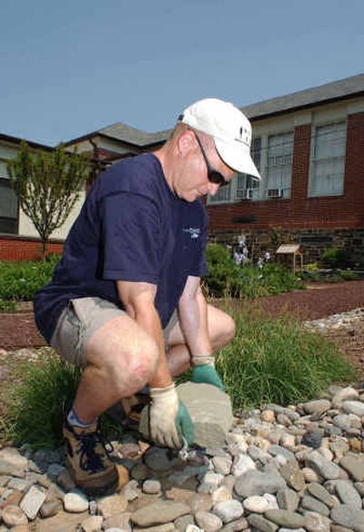 
Eli Glick, a physical therapist and Master Gardener, demonstrates the correct way to lift rocks by bending the knees. 
 (Knight Ridder / The Spokesman-Review)