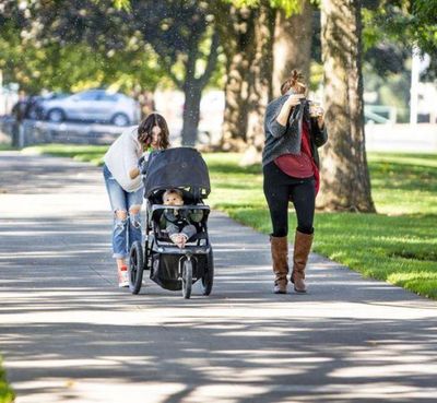 Two women try to protect themselves and a baby from the ash aphids in City Park last week. (Shawn Gust / Coeur d'Alene Press)