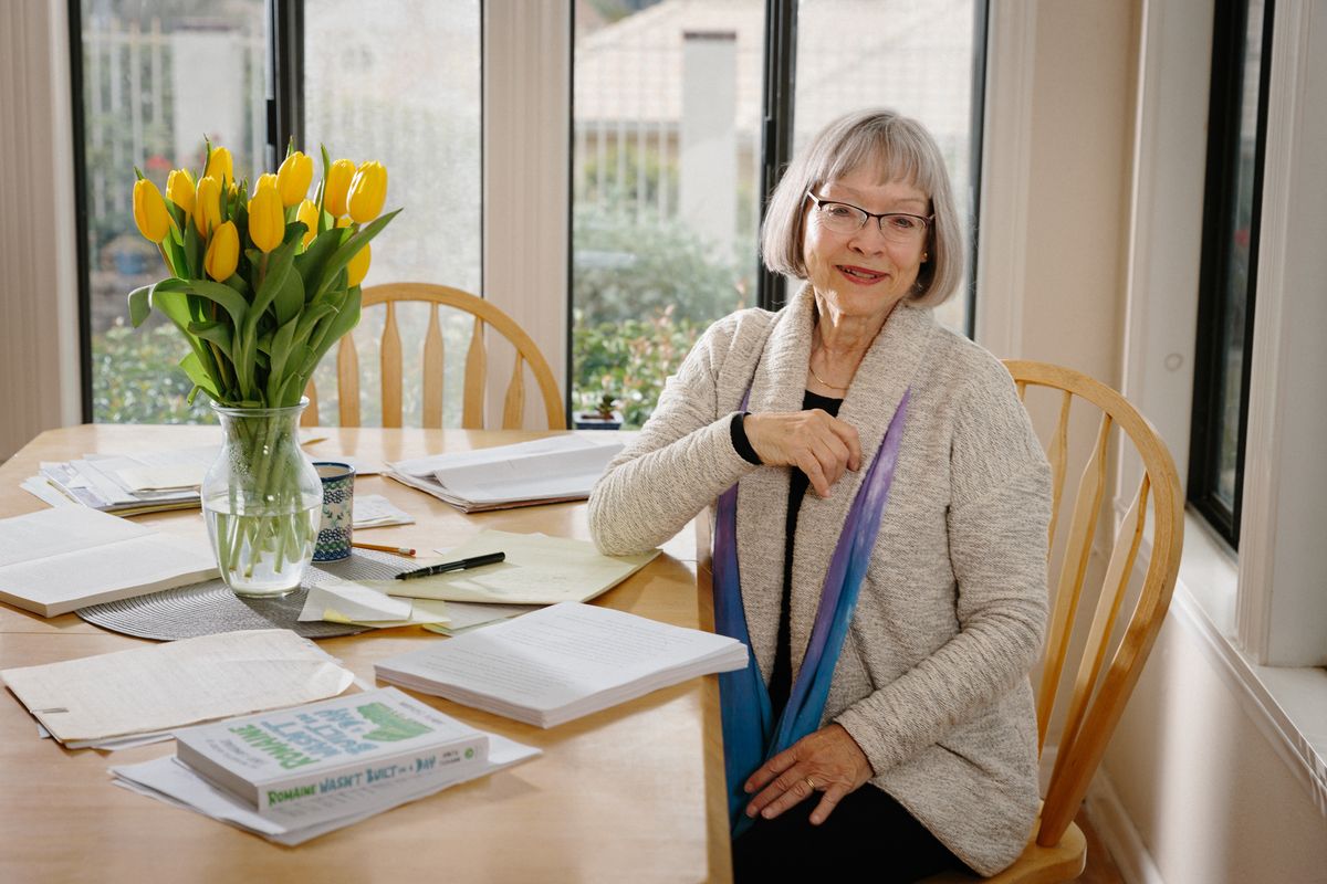 The author Judith Tschann with her new book “Romaine Wasn’t Built in a Day,” at home in Redlands, Calif., Feb. 27, 2023. The new book exploring the origins of common food terms — from bialy to lima bean to bibimbap — is a fascinating history of how we eat and cook.   (STELLA KALININA/New York Times)