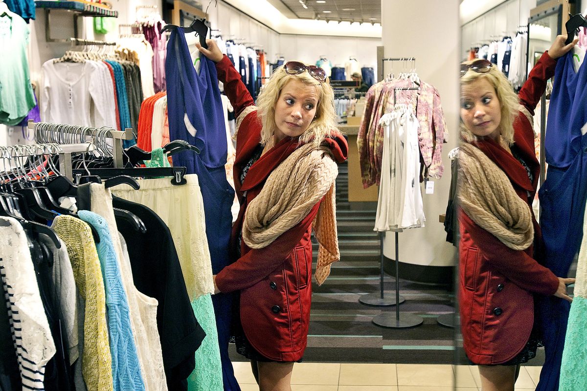 Tiia Lustig, visiting from Finland, uses a full-length mirror to check out a dress while shopping in the Savvy department at Nordstrom in downtown Seattle.
