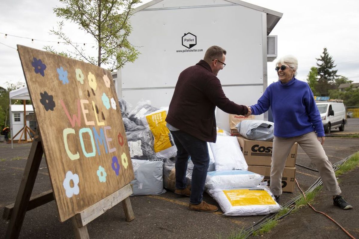 Andy Goebel (center), the executive director of All Good Northwest, shakes hands with Sandy Stienecker, a volunteer with Friends of Multnomah Safe Rest Village. The Multnomah Safe Rest Village is the first of six Safe Rest Villages set to open in 2022. Friends of Multnomah Safe Rest Village delivered blankets, pillows and other items on Thurs., June 9, 2022. All Good Northwest, a social services organization that will operate the shelter, will take over preparation of the site this weekend.  (Dave Killen)
