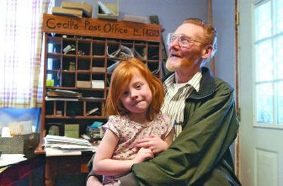 
Mica Postmaster Cecil Boyd shares a moment with his 4-year-old granddaughter, Keely, at the Mica post office Wednesday. Cecil and his wife, Lynn, live in the back of the post office, which has been in the same building since 1902. 
 (J. BART RAYNIAK photos / The Spokesman-Review)