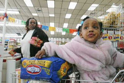 
Lynda Wheeler shops with her daughter, Jaime, 2, shortly after midnight at One Stop Food & Liquors on Chicago's South Side on May 1.  The market doors open at midnight on the first of each month  to let her and  others shop the instant they have access to the new month's allotment of food stamps. Associated Press
 (Associated Press / The Spokesman-Review)