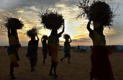
Sudanese women carry firewood at a camp in northern Darfur on Monday where more than 40,000 displaced people live. 
 (Associated Press photos / The Spokesman-Review)
