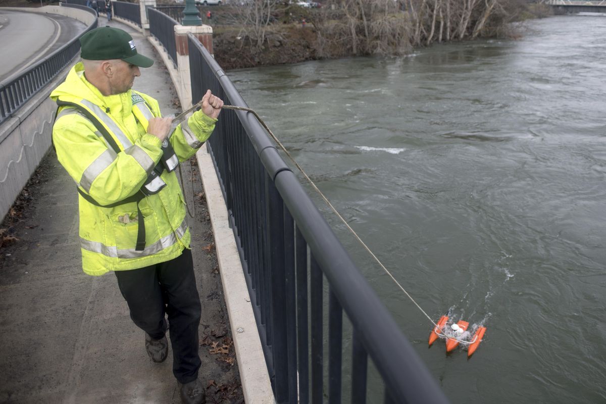 Hydrologic Technician Joe Gilbert maneuvers a raft with test equipement along the Spokane River bridge between WSU Spokane and the Gonzaga University area. The raft used a variety of technologies to estimate the river flows, which is information used by various government, utility and private entities. (Jesse Tinsley / The Spokesman-Review)