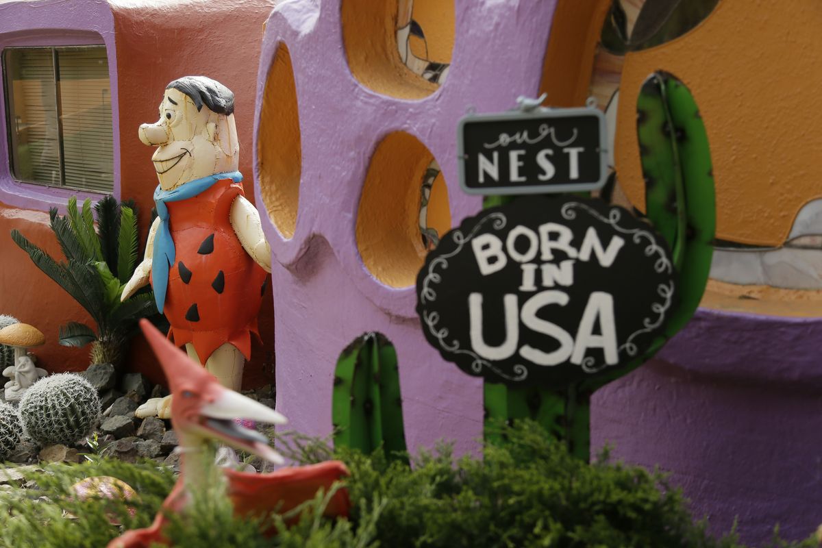 In this Thursday, April 11, 2019 photo, a statue of Fred Flintstone stands near the front entryway of the Flintstone House in Hillsborough, Calif. Technically, the owner of the fanciful Flintstones house in a posh San Francisco suburb settled a lawsuit with the town of Hillsborough. But the agreement will allow Fred and his friends to remain.  (Eric Risberg)