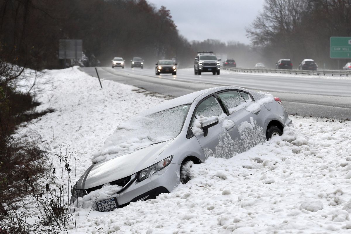 This Thursday, Nov. 15, 2018 photos shows traffic passing by as a car that went off Interstate 684, at the Goldens Bridge exit, during a snowstorm. The first snowfall of the season lingered Friday in the Northeast as thousands of exhausted commuters pointed their fingers at politicians and meteorologists for leaving them creeping along highways or stuck in mass transit hubs. (Frank Becerra Jr. / AP)