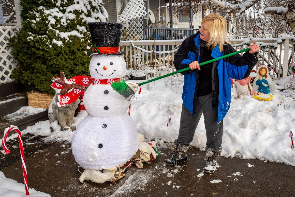 “I’m trying to get as much dug out,” said Bonny Dixon as she brushes the snow from her Christmas decorations and removes them from her front yard on West Mallon Avenue before the next round of heavy snow comes Wednesday night.  (COLIN MULVANY/THE SPOKESMAN-REVIEW)