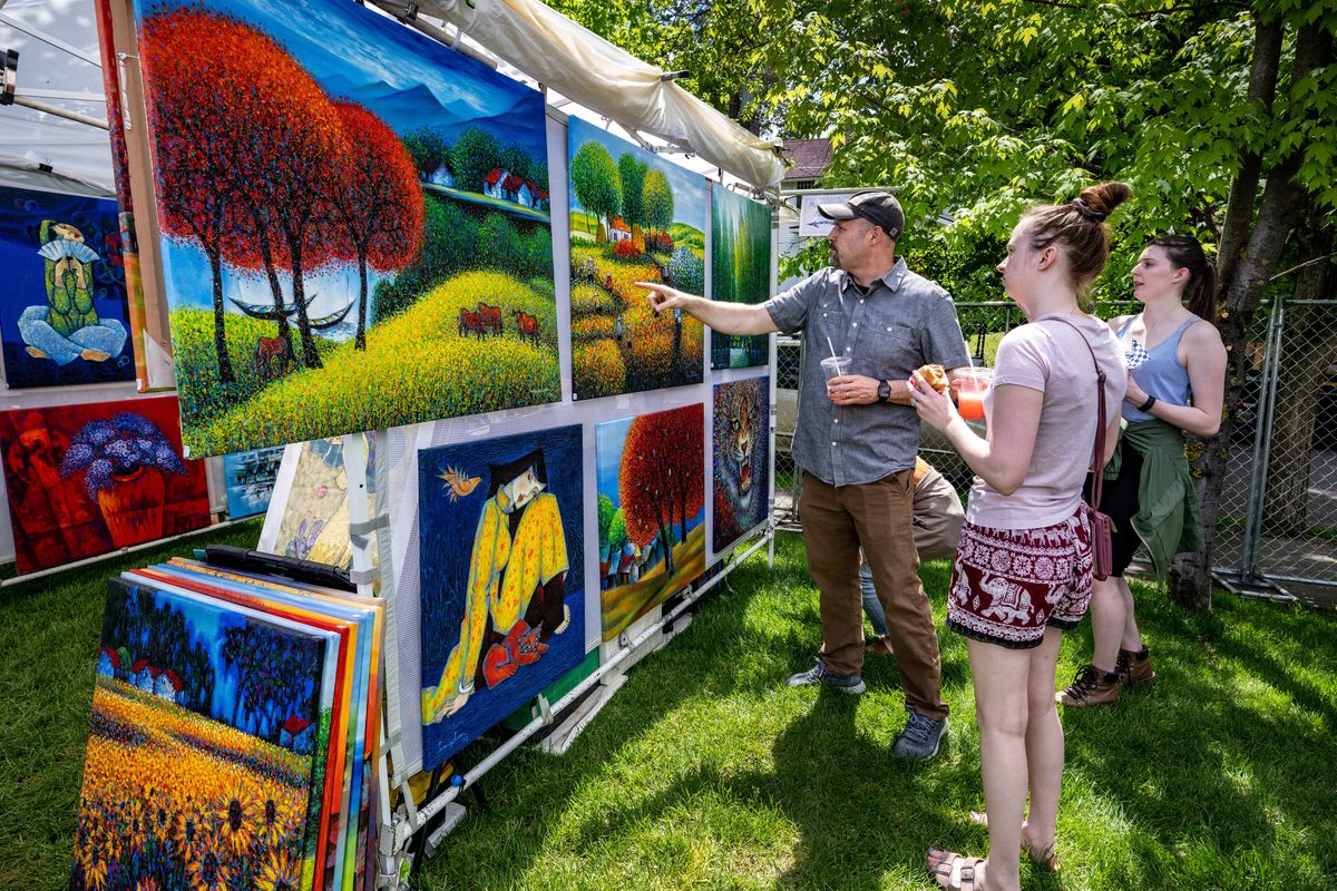 Above: Pottery artist Alan Higinbotham makes a sale of high-fired porcelain mugs Friday at the 37th annual ArtFest on the grounds of the Northwest Museum of Arts and Culture. Below: Grant Erickson, left, Jenny Curry and Meghan Woodford admire artist Hung Pham’s oil and acrylic paintings. ArtFest continues through Sunday.  (COLIN MULVANY/THE SPOKESMAN-REVIEW)