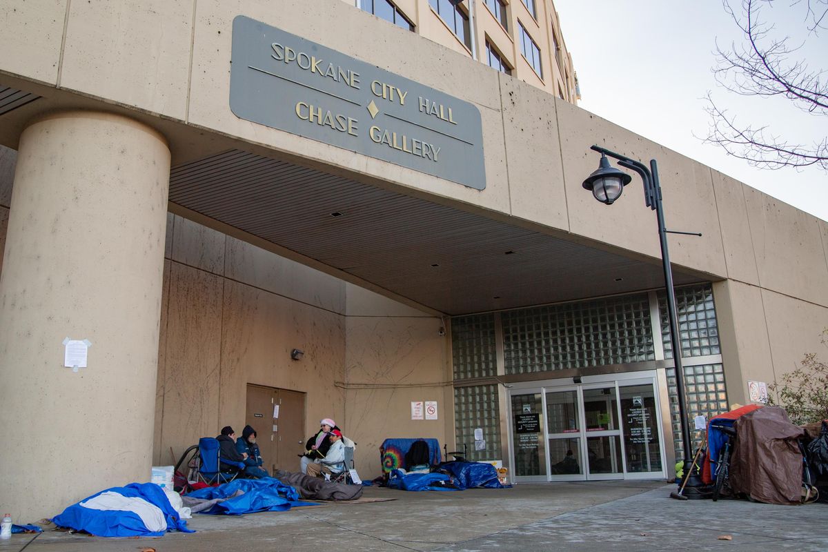 People gather outside of Spokane City Hall on Nov. 25, 2018. A notice was posted on Saturday that any property remaining in this area would be removed at 9:30 a.m. Monday and would be destroyed. (Libby Kamrowski / The Spokesman-Review)