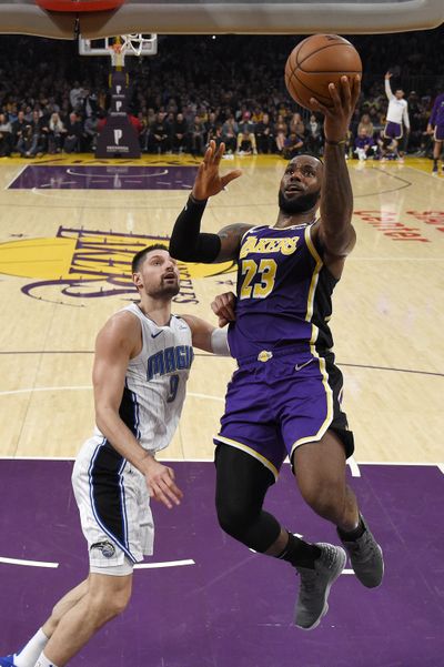 In this Jan. 15, 2020 photo, Los Angeles Lakers forward LeBron James, right, shoots in Los Angeles. The Milwaukee Bucks and Los Angeles Lakers already have just about guaranteed themselves the top two playoff seeds and face a delicate balancing act when the NBA returns to action. They must try to shake off the rust after a 4 ½-month hiatus while also staying as healthy as possible for the postseason. (Associated Press)