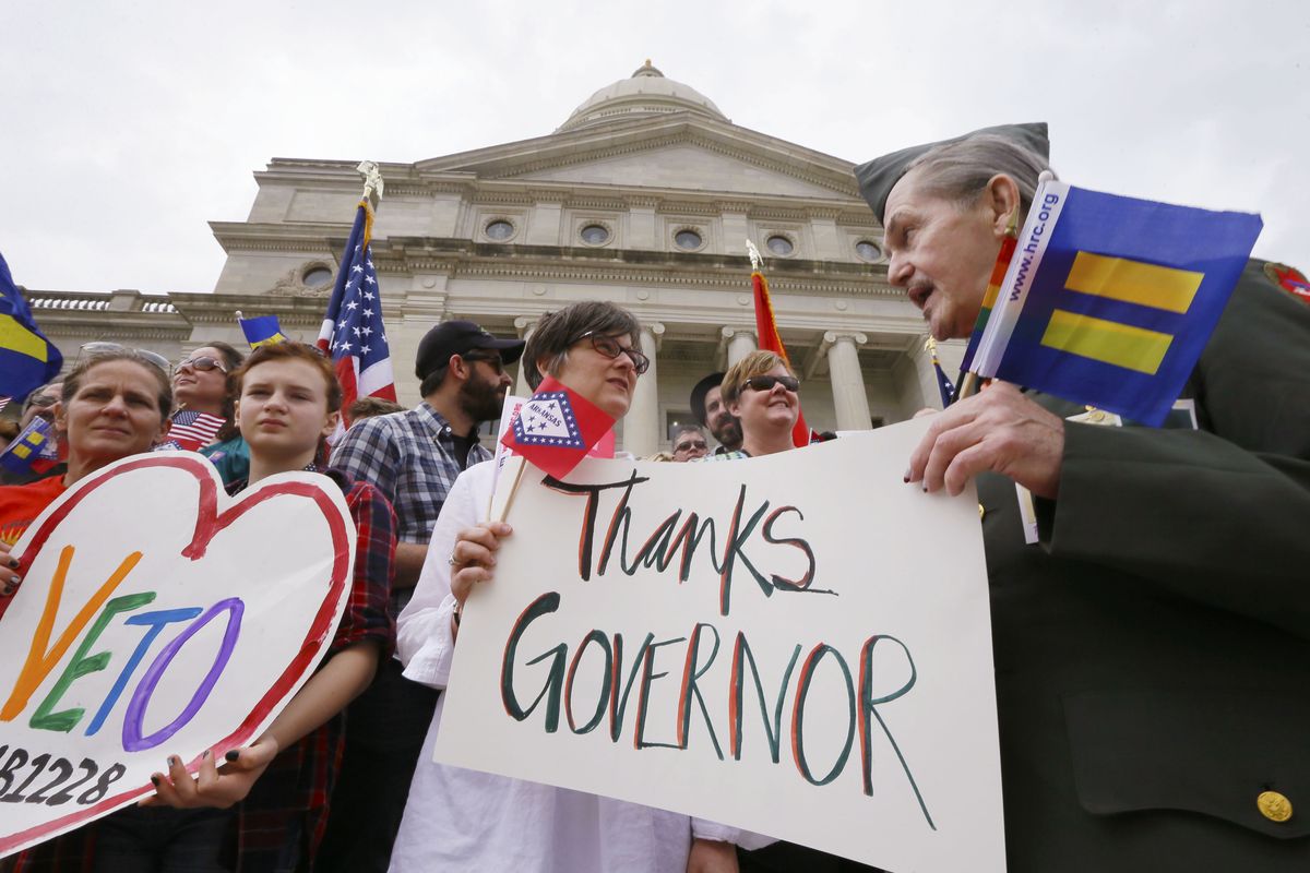 Kristen Hooper, center, and Robert Loyd, right, hold a sign on the steps of the Arkansas Capitol in Little Rock thanking Gov. Asa Hutchinson for calling for changes to a religious objection measure Wednesday. The measure faced a backlash from businesses and gay rights groups. (Associated Press)