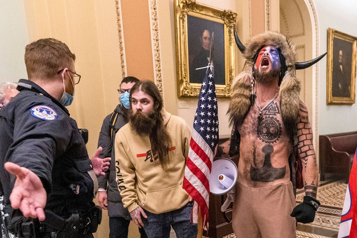 FILE - Supporters of President Donald Trump, including Jacob Chansley, right with fur hat, are confronted by U.S. Capitol Police officers outside the Senate chamber inside the Capitol during the capitol riot in Washington, Jan. 6, 2021. Chansley was sentenced on Wednesday, Nov. 17, 2021, to 41 months in prison for his felony conviction for obstructing an official proceeding. Though he wasn