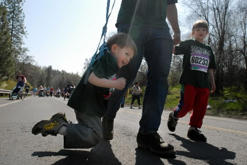 Gerrin LaFleur, 3, picks up his feet and lets his father, Les LaFleur, carry him by his child restraint up Government Way during Bloomsday 2008 on Sunday, May 4, 2008. At right is his sister, Alzera, 6. (Jesse Tinsley / The Spokesman-Review)