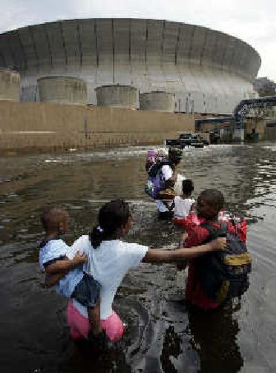 
New Orleans residents hoping to flee rising floodwaters from Hurricane Katrina make their way to the Superdome on Tuesday. 
 (Associated Press / The Spokesman-Review)
