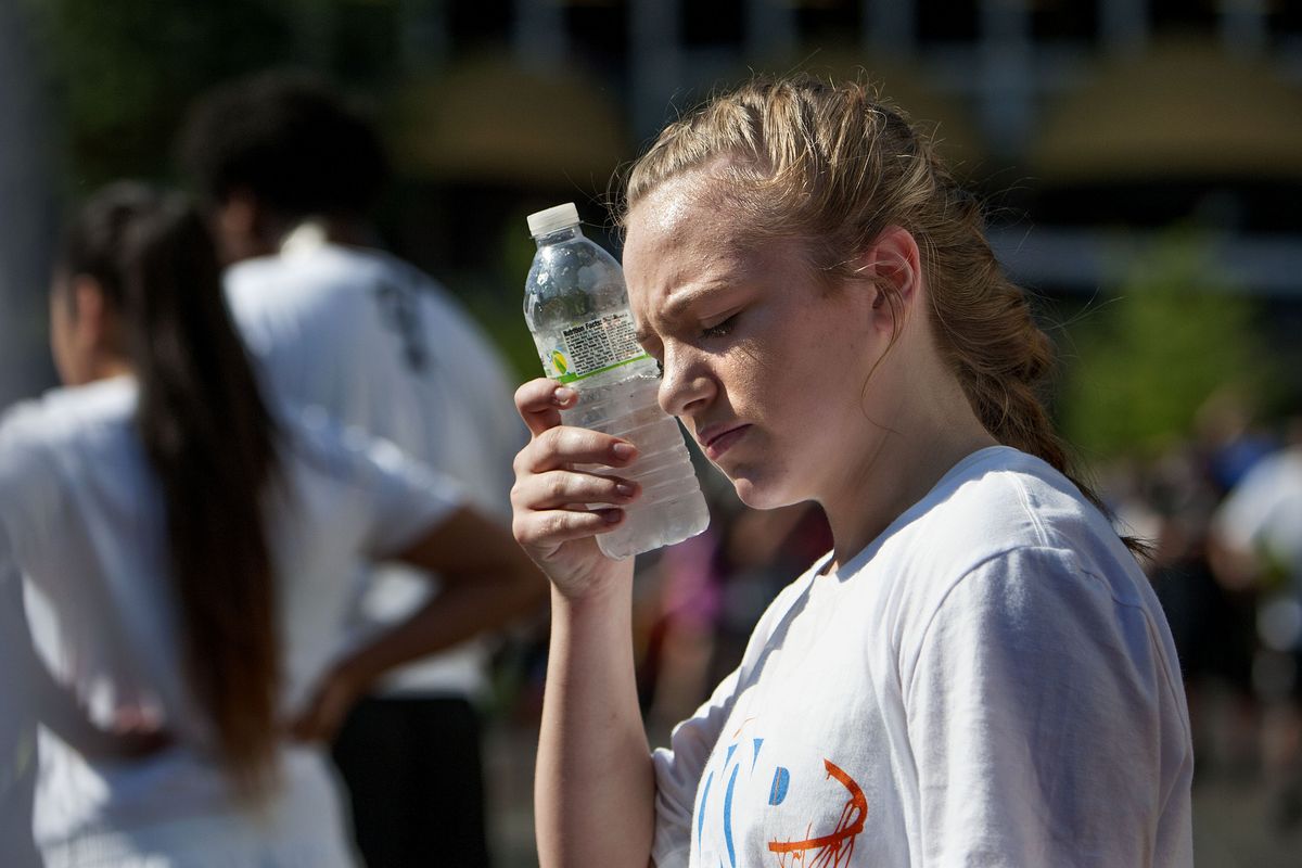 Thirteen-year-old Riley Hall, of Spokane, uses her water bottle to battle the heat during Hoopfest on Saturday. Hoopfest Sunday set the all-time June record of 105 degrees. (Kathy Plonka)