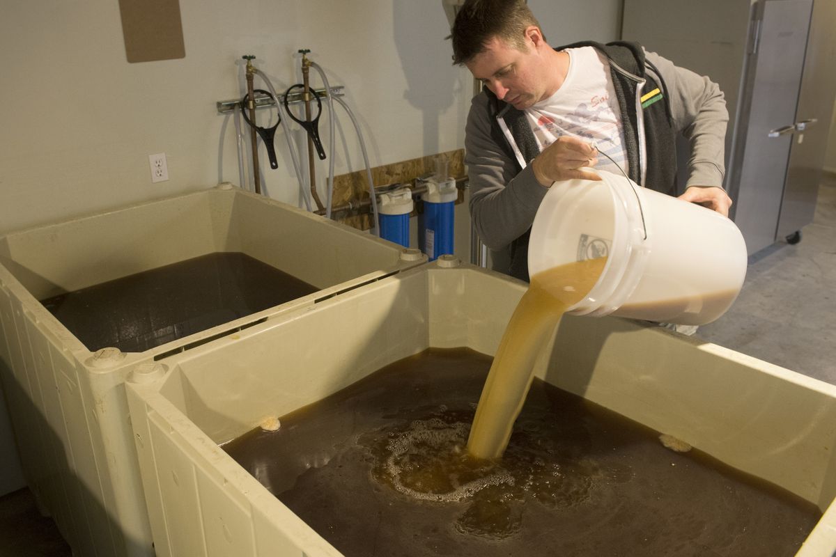 Michael Thompson, of 21 Window Distillery, pours a mixture of yeast and apple juice into a giant vat of apple juice, the start of the production of vodka from apples on Friday. Thompson runs the tiny distillery and sells all its products to a distributor. (Jesse Tinsley)