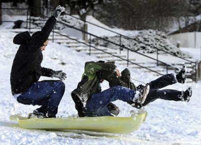 
The Bran brothers, from left, Jose, Alonzo and Edwaur,  crash-land their sled after flying off a jump on the hill behind the West Valley City School. 
 (Photos by Dan Pelle / The Spokesman-Review)