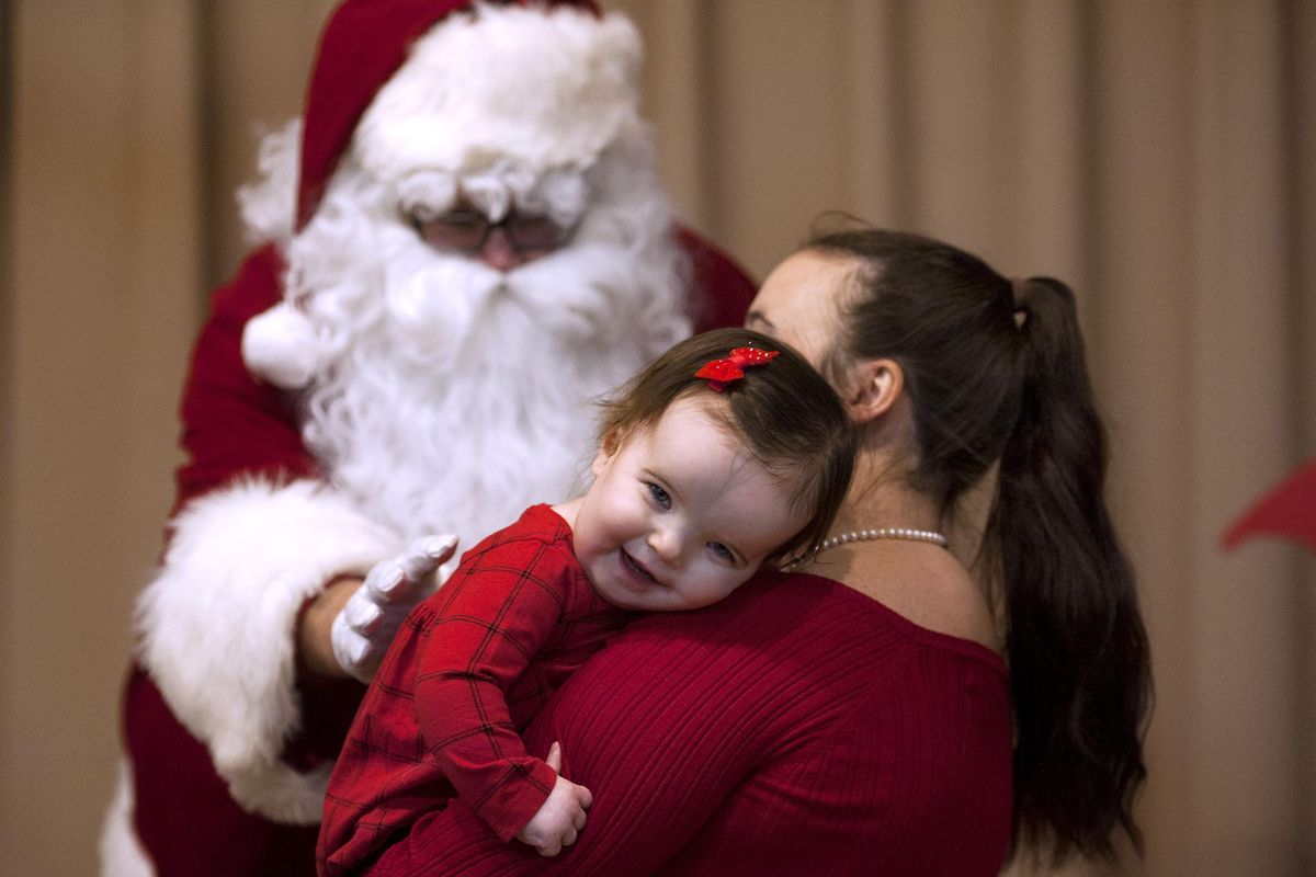 Naomi Porter, 15 months, holds onto her mother Shanna before visiting with Santa as part of Spokane HOPE’s annual Ho Ho HOPE Santa Breakfast at Sinto Senior Center in Spokane on Saturday, Dec. 1, 2018. She has a rare genetic condition called osteopathia striata with cranial sclerosis syndrome. She receives services from Spokane Hearing Oral Program of Excellence (HOPE). They provide early intervention auditory and language therapy to children with hearing loss during the early years of rapid brain development. (Kathy Plonka / The Spokesman-Review)